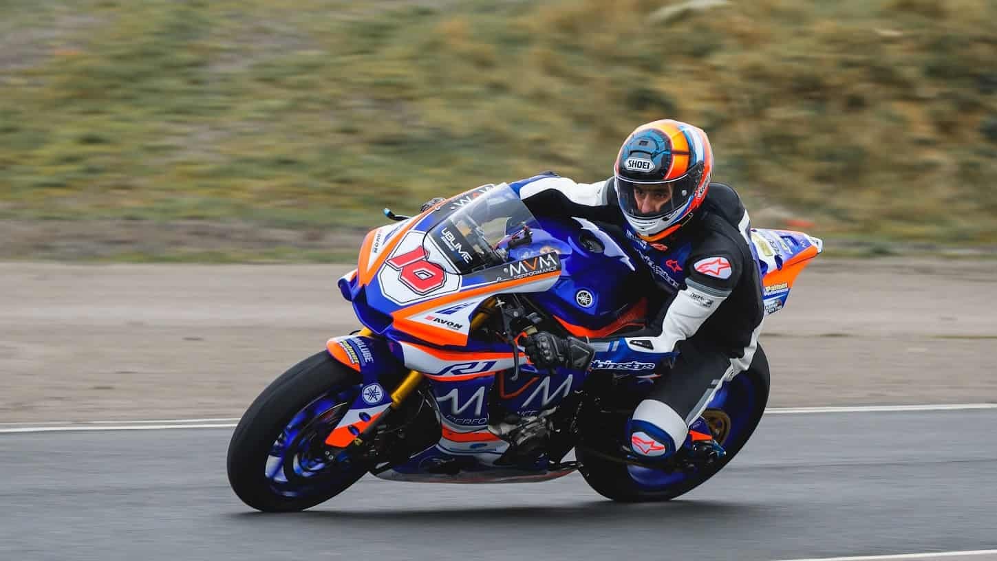 Rider leaning into a corner on a blue-orange Yamaha sport bike during a track day, showcasing high-performance handling