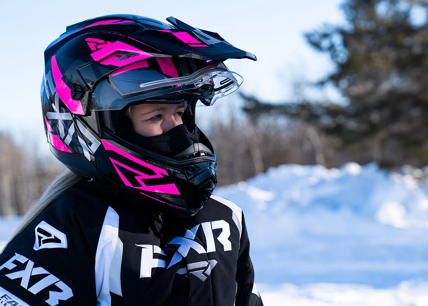 Rider wearing an FXR snowmobile helmet with a clear shield designed for cold-weather visibility