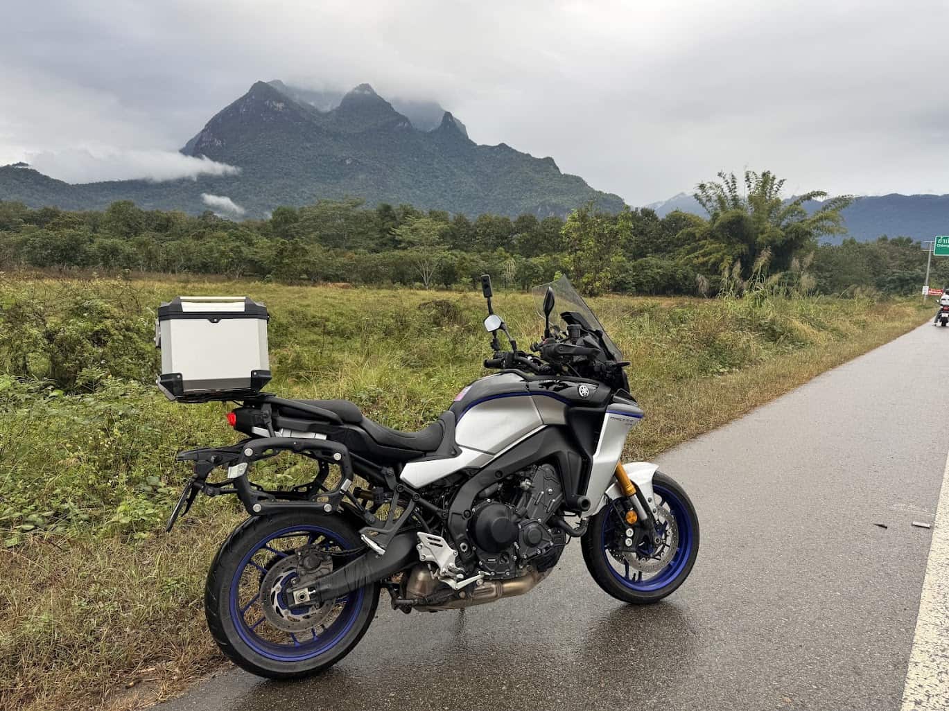 Adventure motorcycle with side case parked on a scenic roadside, representing the importance of insuring aftermarket accessories.