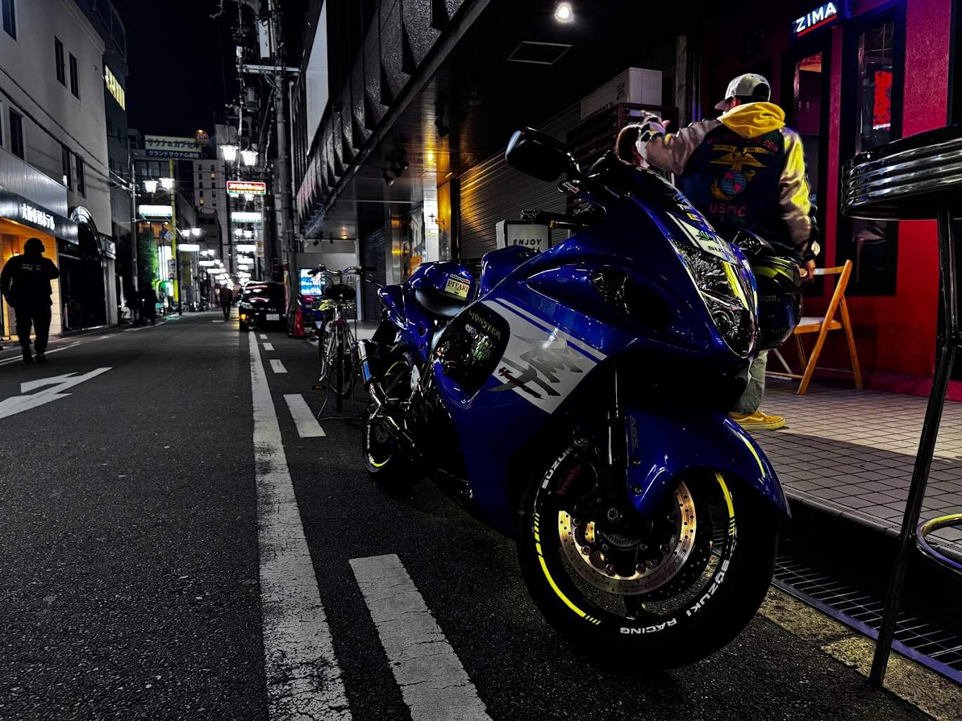Sport motorcycle parked on a city street at night near a café entrance