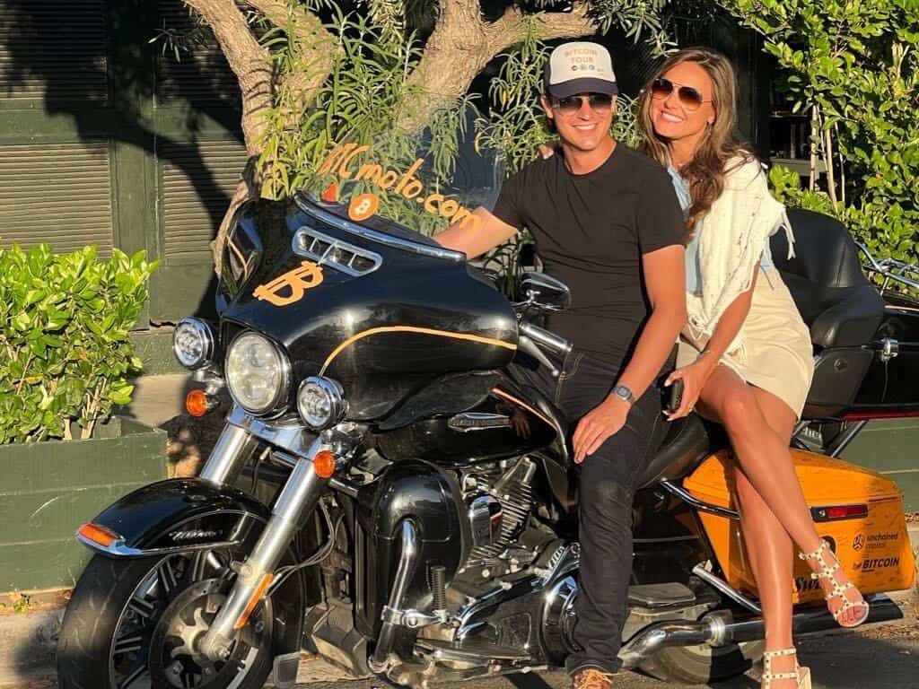 Smiling couple sitting on a touring motorcycle, representing loyal riders who benefit from long-term insurance discounts and rewards.