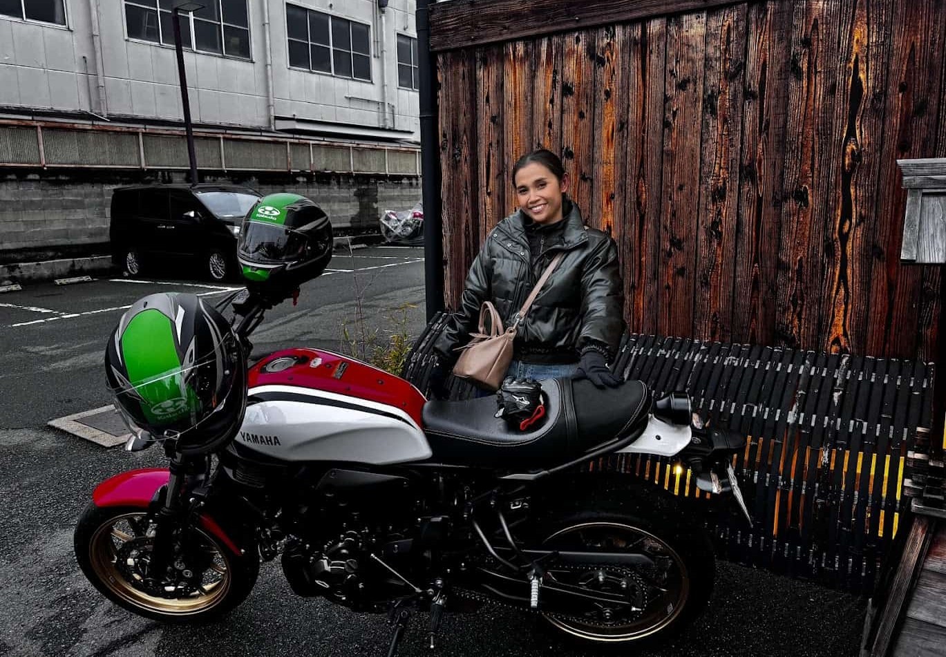 Smiling rider sitting beside a parked Yamaha motorcycle on a cool day, capturing a laid-back, low-mileage riding moment