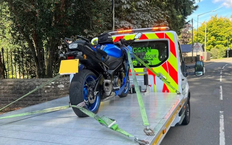 Motorcycle secured on a tow truck, representing roadside assistance and trip interruption coverage for riders.