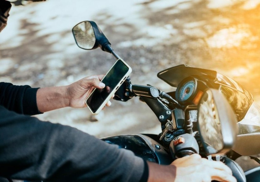 Motorcyclist using a smartphone to record odometer reading on their bike