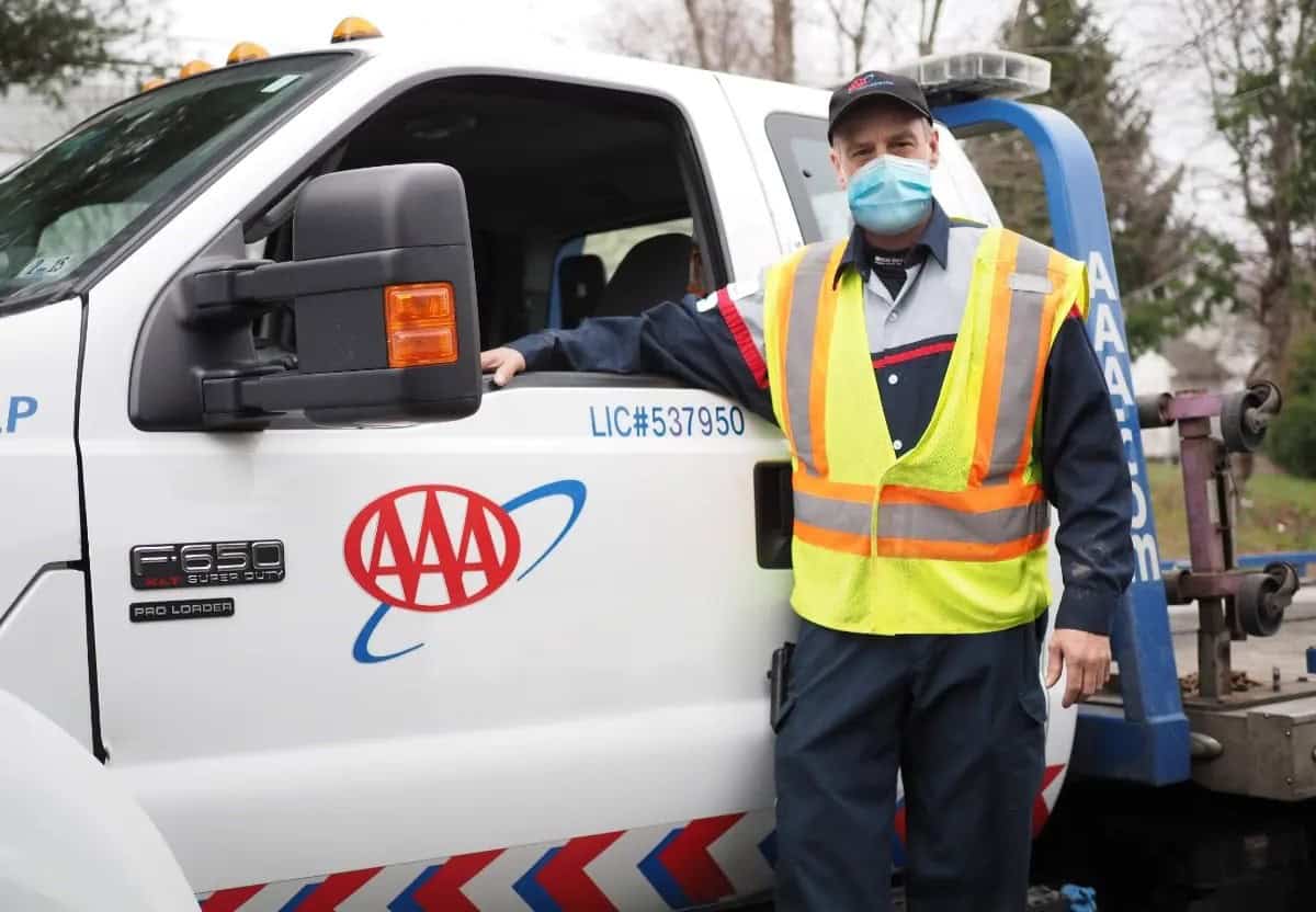 AAA roadside technician beside a tow truck during a service call