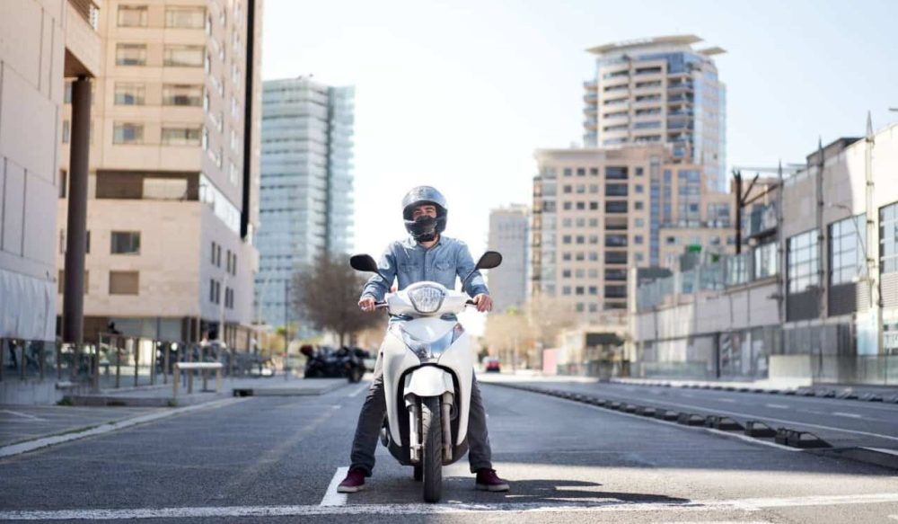 Rider on a small commuter scooter in the city, ready to start a daily ride to work