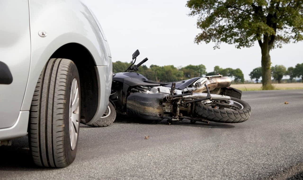 Motorcycle accident showing a car and fallen bike — represents liability coverage for at-fault crashes.