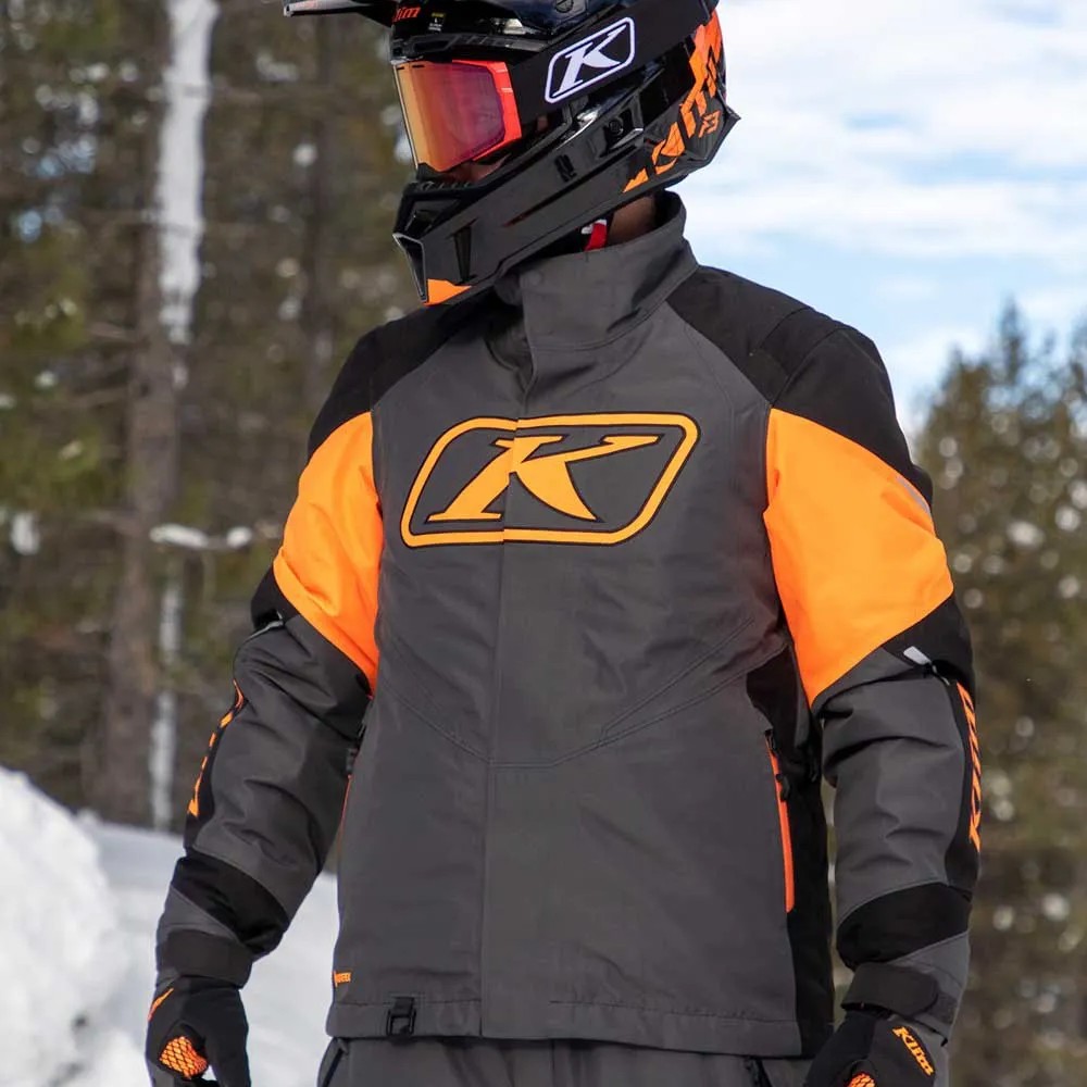 Klim Klimate snowmobile jacket in orange and grey worn on a winter trail