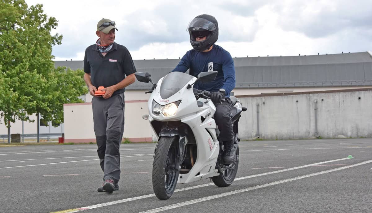 Motorcycle safety instructor guiding a rider during a training session, representing military and group insurance discount programs.