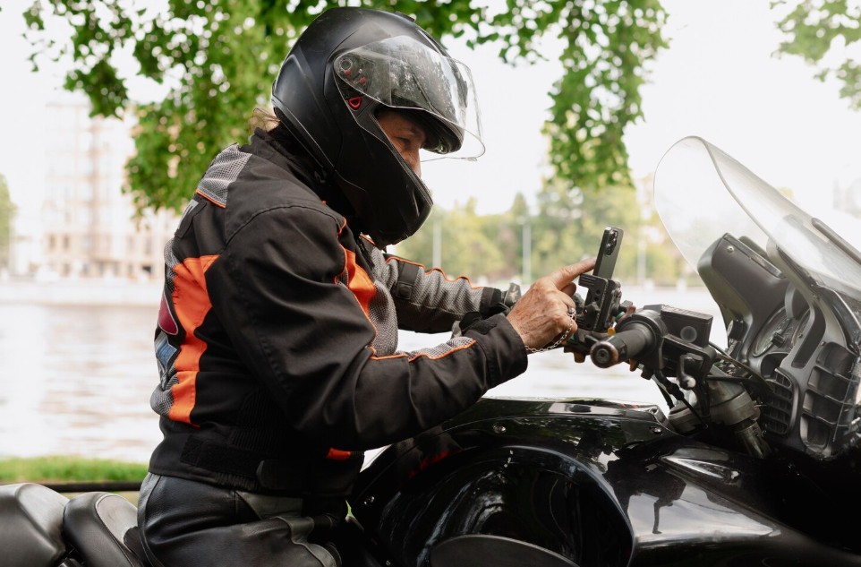 Motorcyclist checking a phone-mounted app before a ride, representing pay-per-mile or usage-based motorcycle insurance options.