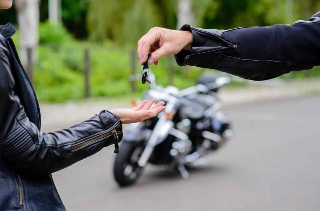 Motorcyclist handing over bike keys for a motorcycle rental