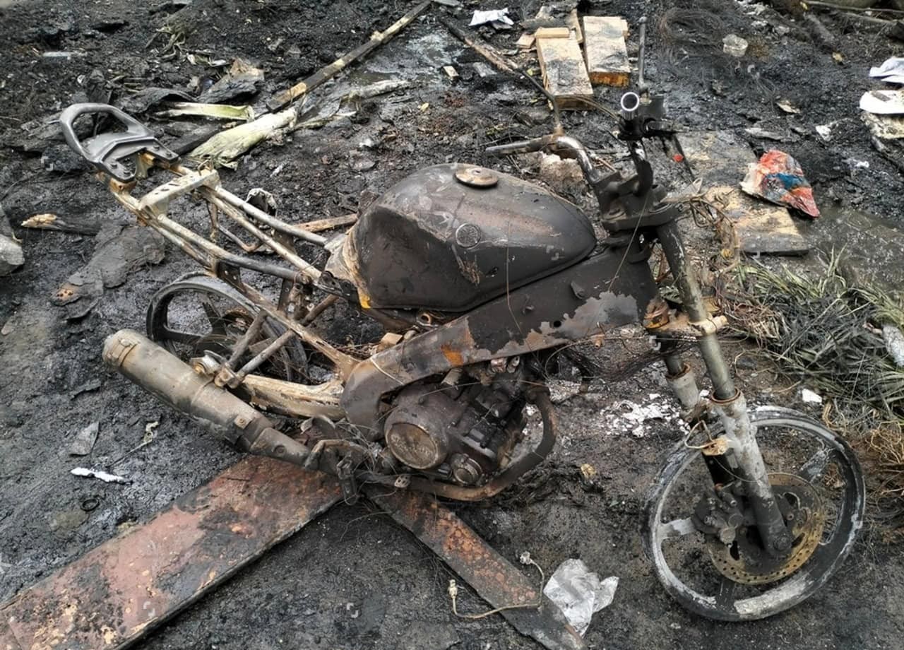 Burned and damaged motorcycle after a fire accident showing total destruction and loss