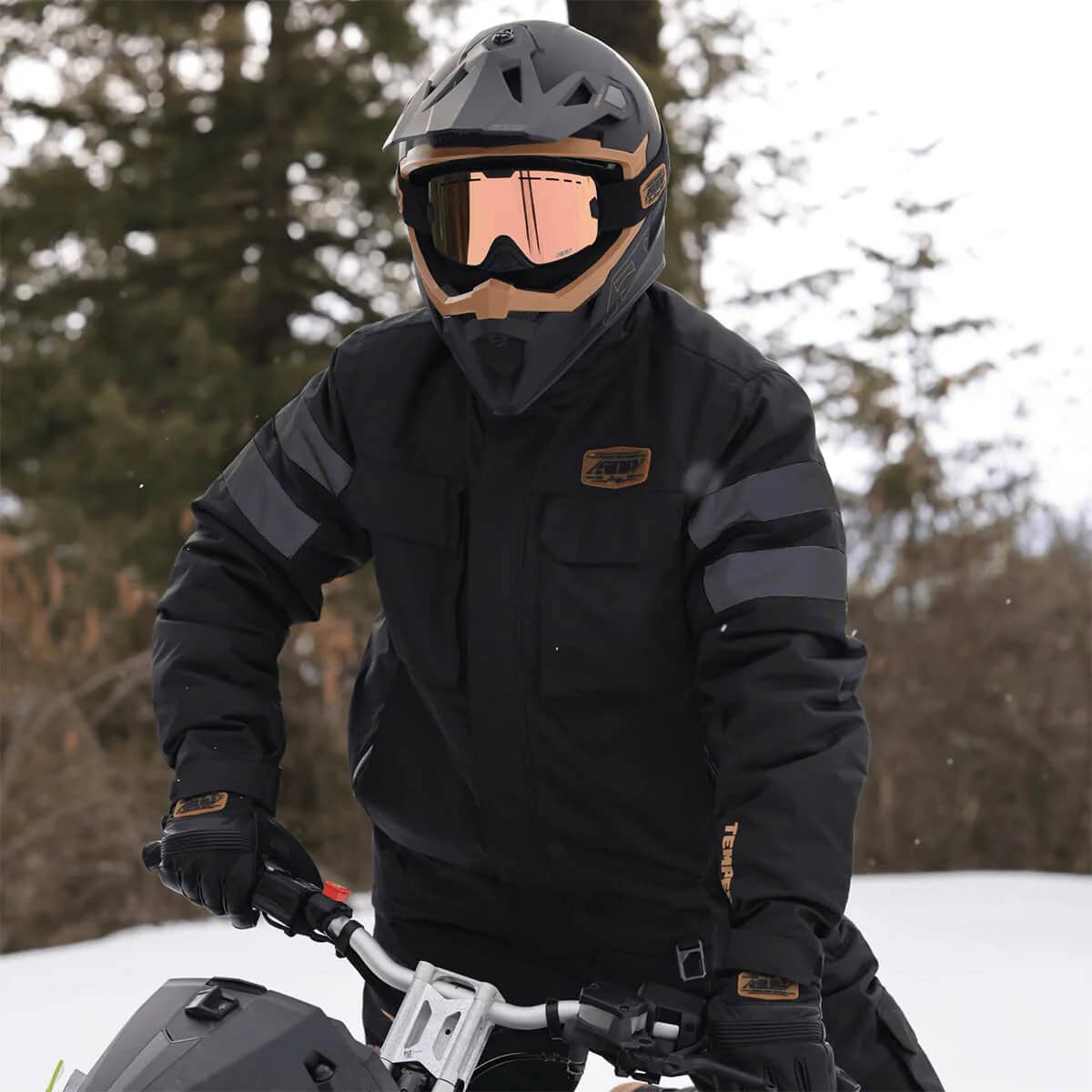 Rider wearing the 509 Temper Insulated Jacket while snowmobiling in winter terrain