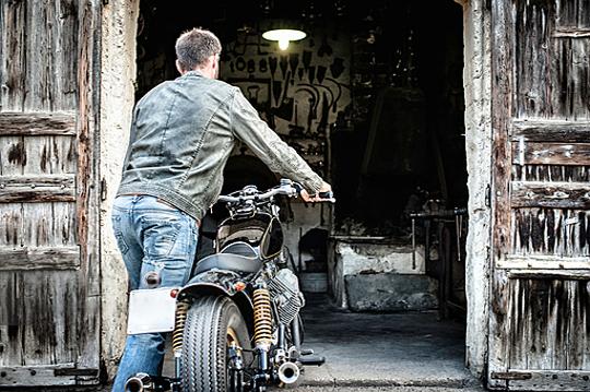 Motorcyclist pushing bike into a garage for winter storage