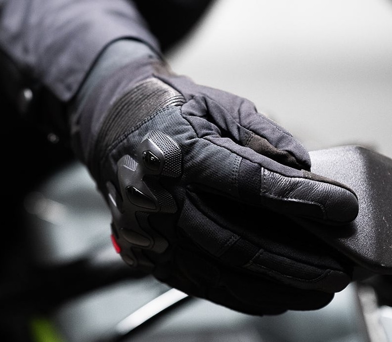 Close-up of motorcycle glove using touchscreen on bike control panel