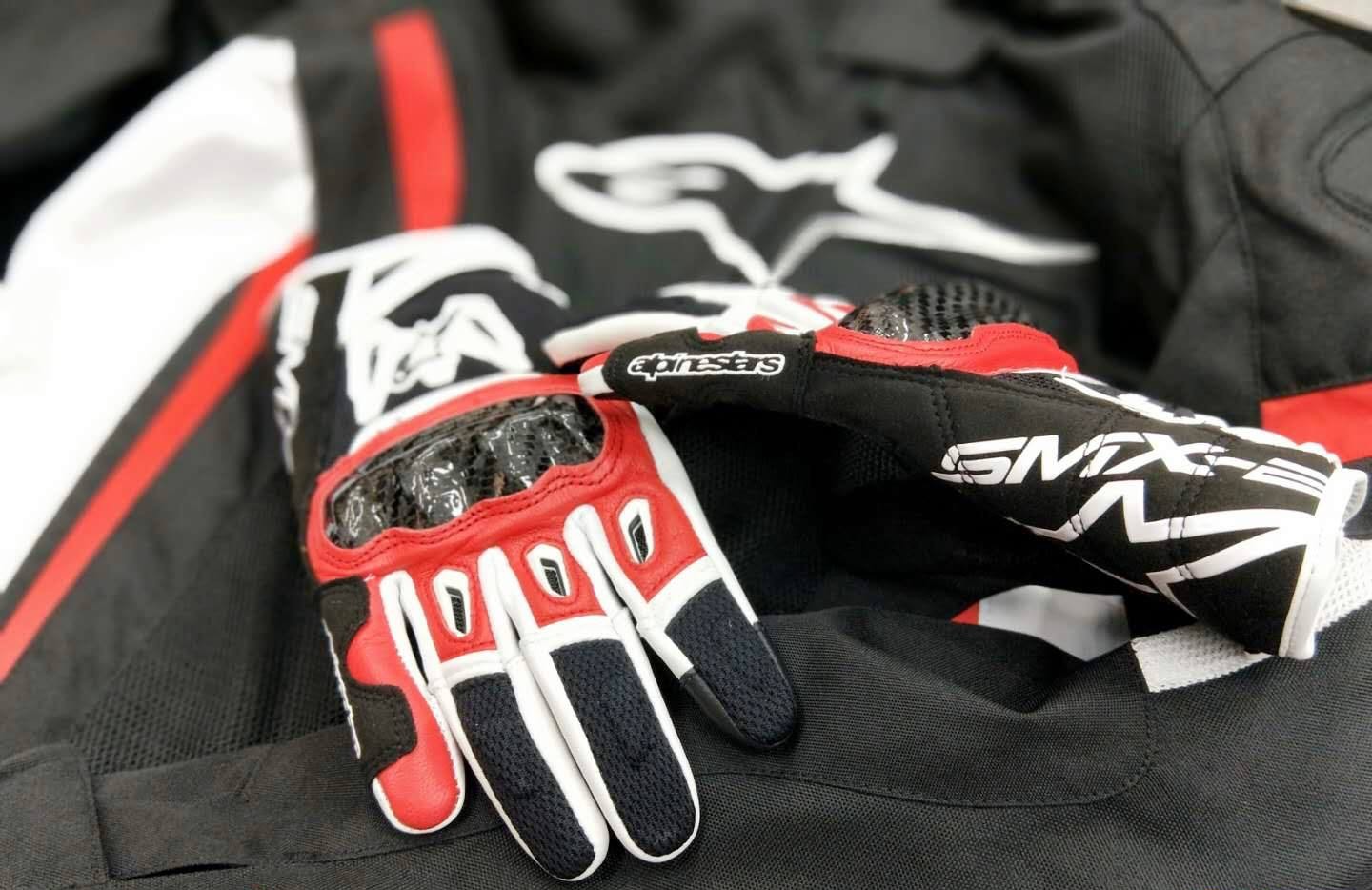 Alpinestars SMX-2 Air Carbon V2 motorcycle gloves with carbon knuckle protectors placed on a riding jacket