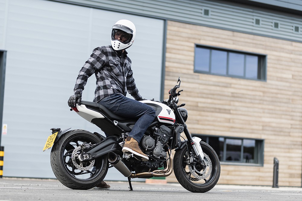 Motorcyclist wearing casual-style riding jeans sitting on a modern motorcycle in an urban setting