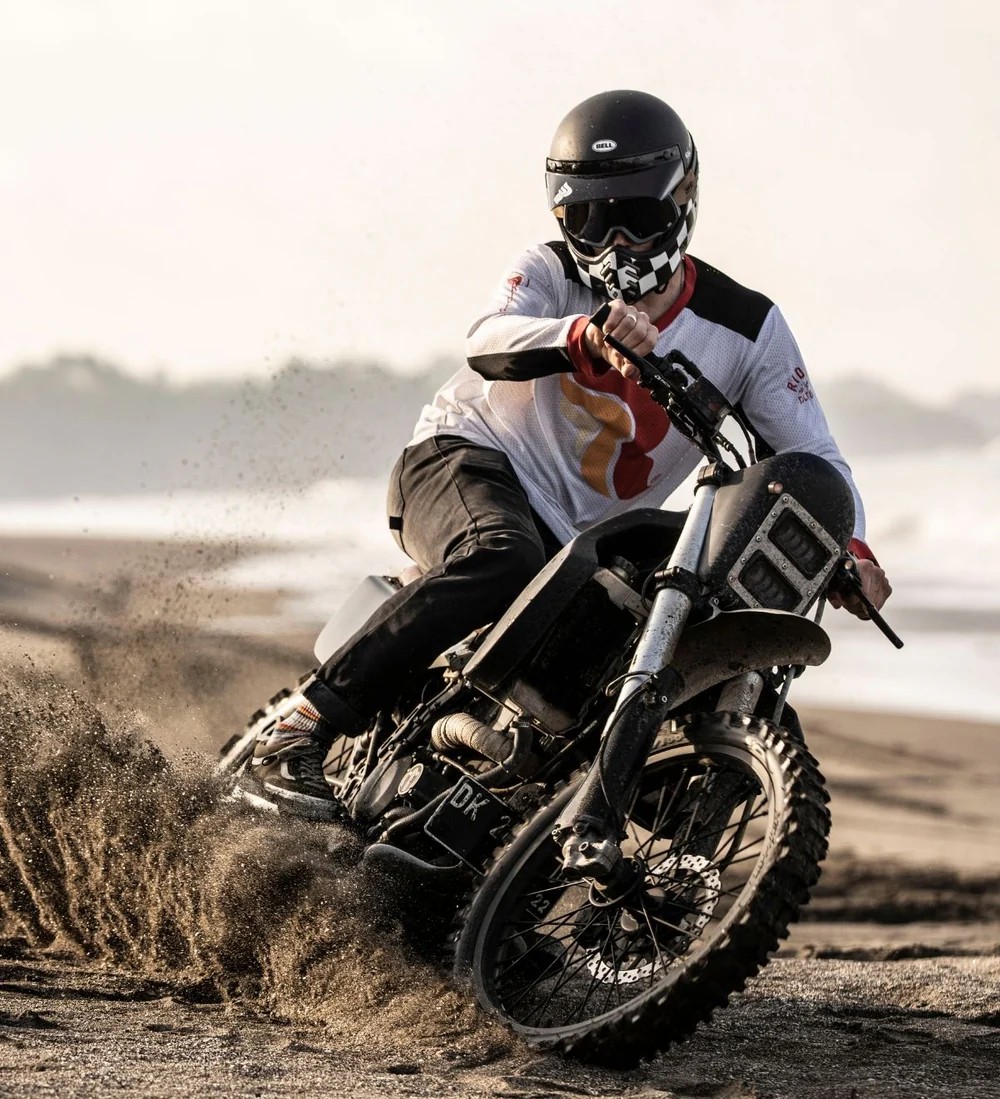 Motorcycle rider sliding through sand wearing slim-fit protective riding jeans with integrated armor