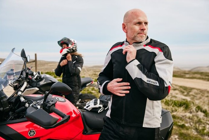 Rider wearing a Sedici Federico 2 Mesh motorcycle jacket standing beside a sport-touring bike outdoors