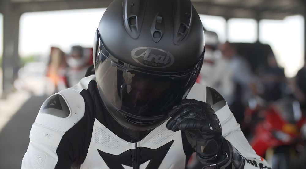 Rider wearing Arai Corsair-X helmet in a track setting with full riding gear