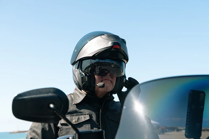 Rider wearing HJC RPHA 91 modular helmet with chin bar flipped up and integrated microphone