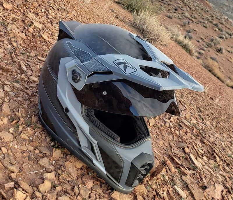 Klim Krios Pro helmet with carbon fiber shell and peak visor resting on rocky terrain