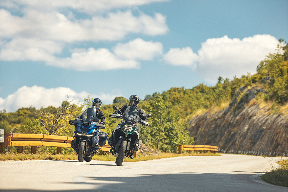 Two riders wearing Schuberth C5 modular helmets touring on adventure motorcycles through a mountain road