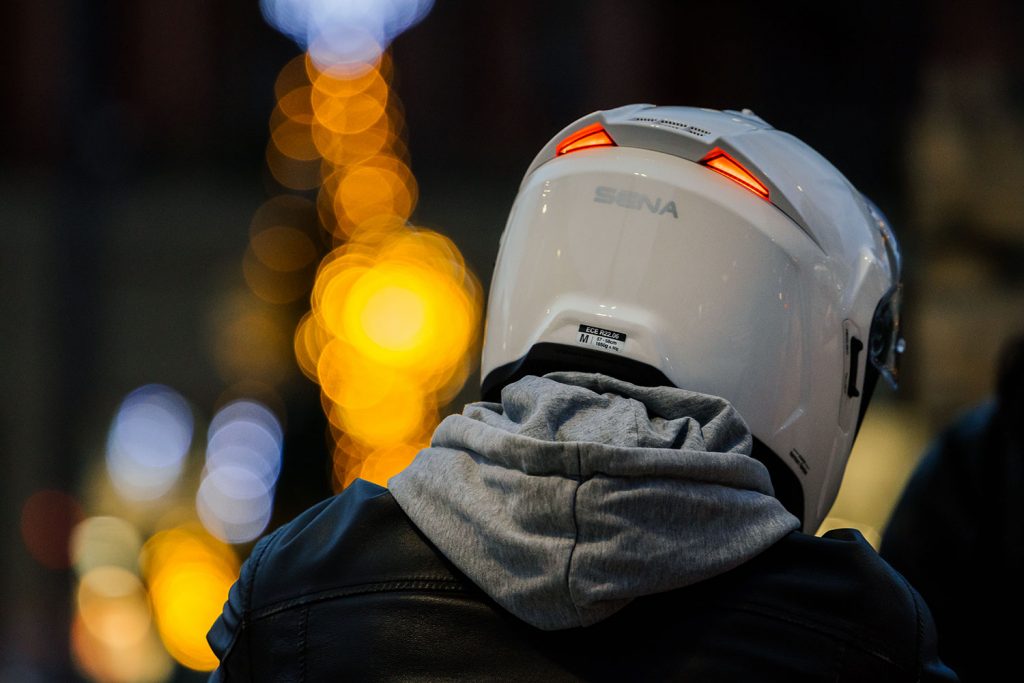 Rear view of a rider wearing a Sena Phantom helmet with illuminated rear safety lights